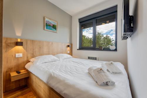 a bedroom with a large white bed with a window at Zlatna zona 59 (Titova vila) in Zlatibor