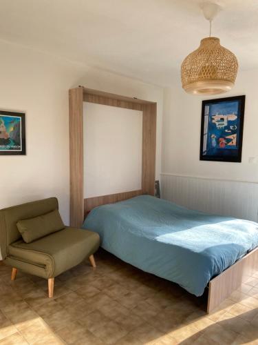 een slaapkamer met een bed en een stoel bij Studio lumineux en bordure de verdon in Gréoux-les-Bains