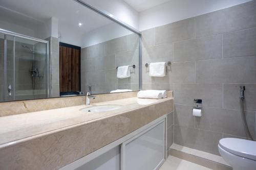 a bathroom with a sink and a mirror and a toilet at Hôtel l'Europe in Djibouti