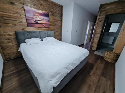 uma grande cama branca num quarto com uma parede de madeira em נופש אזאר-וילה em ‘Isfiyā