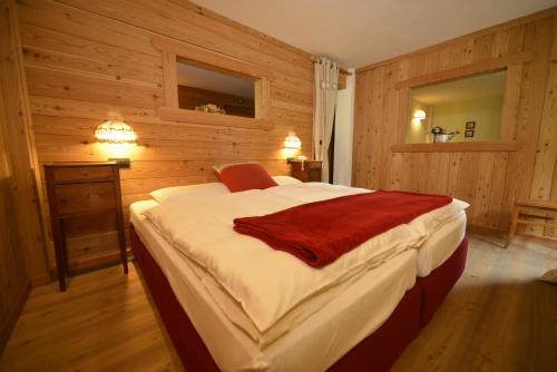 una camera da letto con un grande letto e pareti in legno di Albergo Alpenrose Ski&Bike Mountain Hotel a Gressoney-Saint-Jean