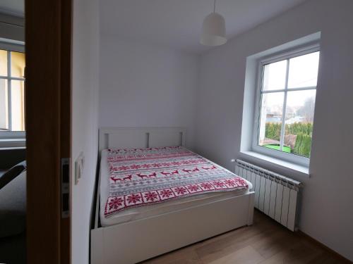 a bed in a white room with a window at Apartamenty Kościuszki in Stronie Śląskie