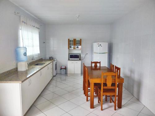 cocina con mesa, sillas y nevera en Amplo Apartamento na Pinheira en Palhoça