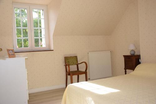 1 dormitorio con 1 cama, 1 silla y 1 ventana en La ferme des Cailloux, en Sassay