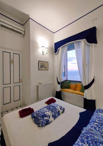 a bedroom with a bed and a window with a couch at Villa Marunnella in Praiano