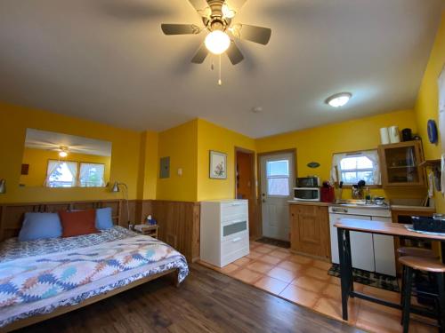 a bedroom with a bed and a kitchen with yellow walls at Trailside Accommodations and Outdoor Adventures in Birch Plain