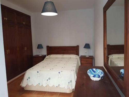 ein Schlafzimmer mit einem Bett, einem Tisch und einem Spiegel in der Unterkunft Apartamento El Coral in Famara