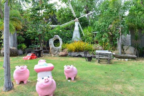 three pig statues in a yard with a windmill at Rayonghouse Resort in Rayong