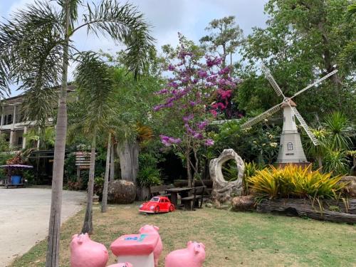 a garden with a windmill and some pink pigs at Rayonghouse Resort in Rayong
