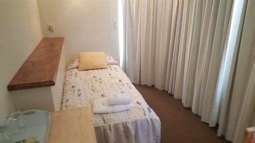 una pequeña habitación con cama y aseo en Hostería Esturion Village en Villa Gesell