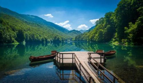 a dock in the middle of a lake with two boats at Modern Mountain - Apartment Najomi in Kolašin