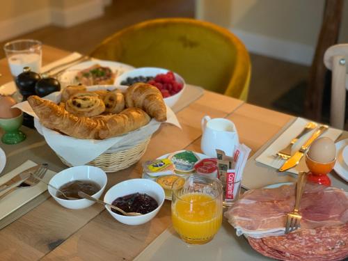 a table with a basket of bread and other breakfast foods at Les Terrasses des Falizes B&B in Rochefort