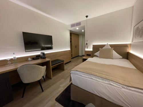 a hotel room with a bed and a desk and a television at Landhaus Bruckmann in Saerbeck