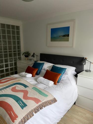 a bedroom with a large bed with orange and blue pillows at Beach Apartment, Watergate Bay, Newquay in Newquay