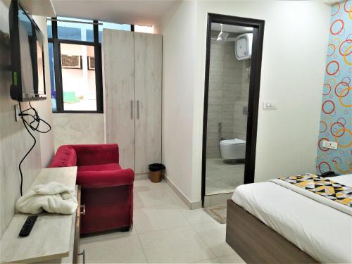 a bedroom with a bed and a red chair and a bathroom at Hotel Le Heritage , Nizamudin Railway Station in New Delhi