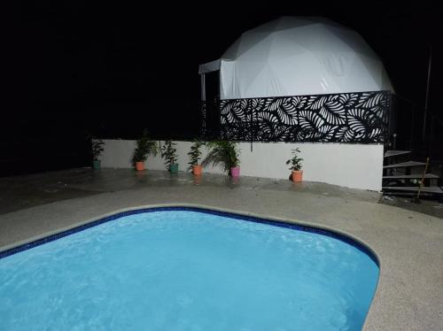 a blue swimming pool with a dome in the background at HOTEL, VILLAS y GLAMPINGS MYA -PUERTO VIEJO, Limon, CR in Puerto Viejo