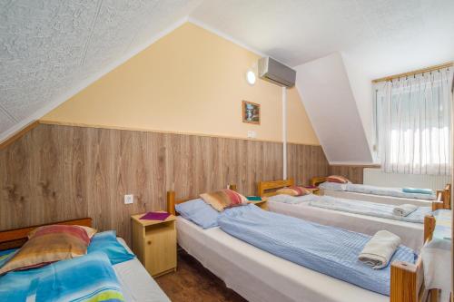 a attic bedroom with two beds and a tub at Füredi Apartman in Tiszafüred