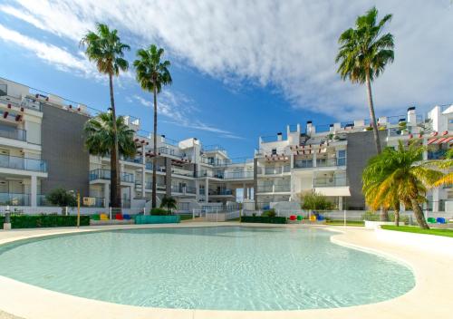 una piscina frente a un edificio con palmeras en Apartamento Victoria Playa III con una gran terraza, en Denia