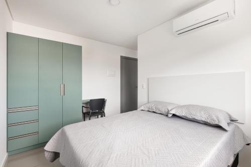 a white bedroom with a bed and a desk at Parador Campeche in Florianópolis