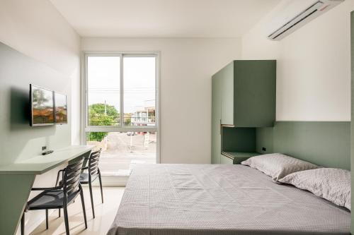 a bedroom with a bed and a desk and a window at Parador Campeche in Florianópolis
