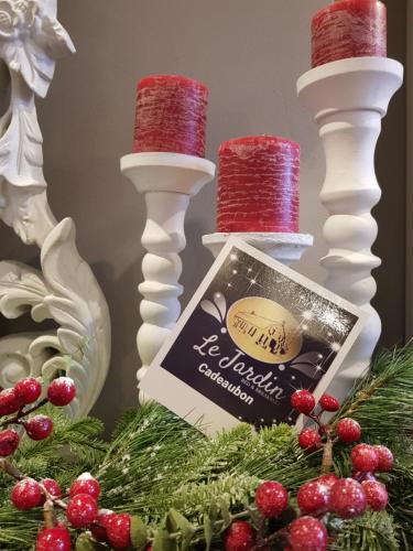 a christmas centerpiece with two white candles and a christmas tree at B&B Le Jardin in Pelt