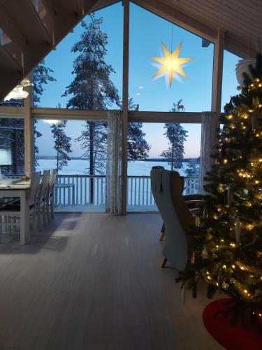 a christmas tree in a room with a view of the ocean at Villa Sirius Sieri, nice Log-Cottage by the lake in Rovaniemi
