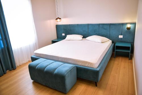 a bedroom with a bed with a blue headboard and a blue bench at Hotel Jurgen in Rinas