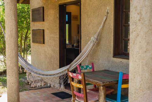 a hammock on the porch of a house with a table and chairs at Pousada Gopak in Praia do Rosa