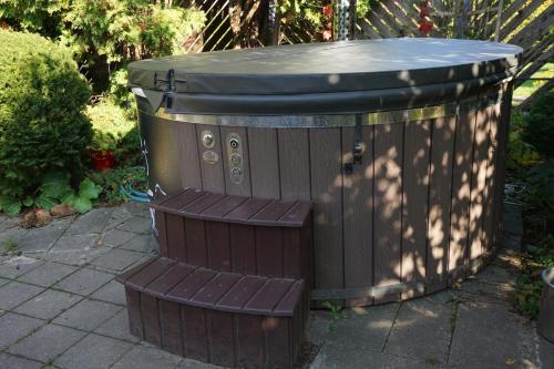 a wooden tub with a bench in a yard at Home for Guests Lakštingala in Šiauliai