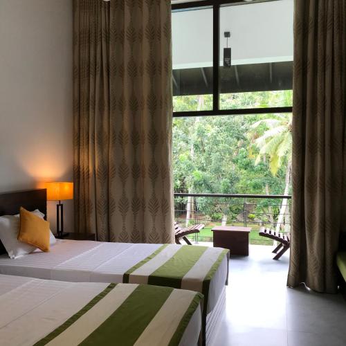 a bedroom with a bed and a large window at Nature Trails Boutique Hotel in Unawatuna