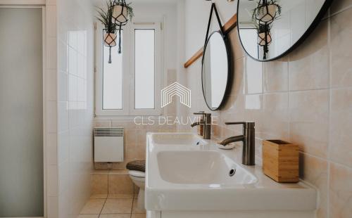 a bathroom with a sink and a toilet and a mirror at La Deauvillaise CLS Deauville in Deauville
