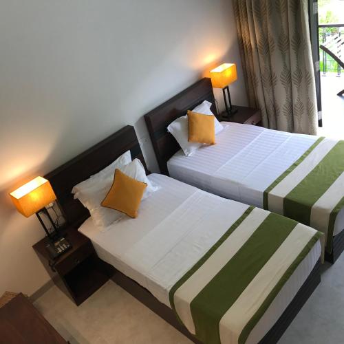 a hotel room with two beds with yellow pillows at Nature Trails Boutique Hotel in Unawatuna