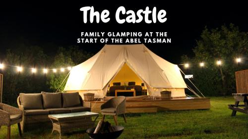 a large white tent with a couch and chairs at The Barn Cabins & Camp in Marahau