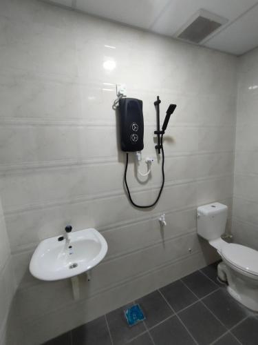 uma casa de banho com um lavatório e um telefone na parede em SENGGARANG HOMESTAY em Parit Kadir