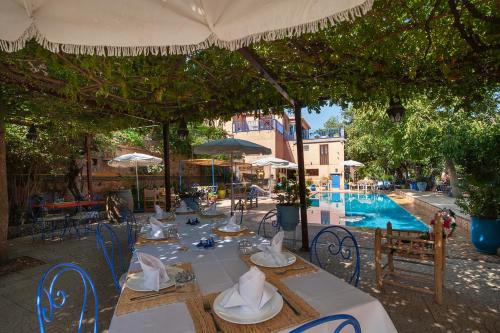 a table with chairs and an umbrella next to a pool at Auberge le Maquis in Aghbalou