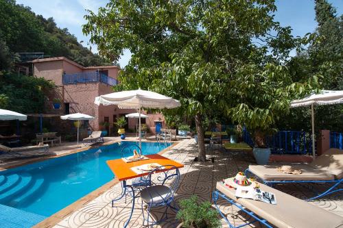 a swimming pool with tables and chairs and umbrellas at Auberge le Maquis in Aghbalou