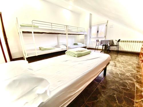 a bedroom with two bunk beds and a table at Hostel albergue Paradiso in Hinojedo