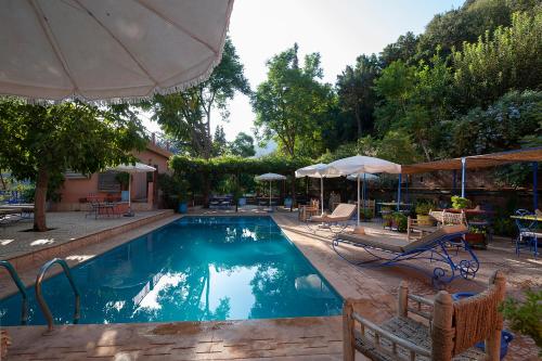 a swimming pool with chairs and umbrellas in a yard at Auberge le Maquis in Aghbalou
