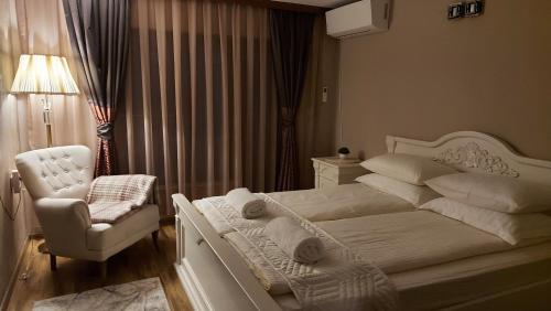 a bedroom with a white bed and a chair at Студио Лидия in Velingrad