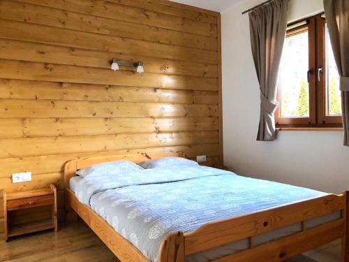a bed in a room with a wooden wall at Chatki u Oli in Baligród