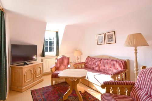 a living room with a couch and a tv at Landhotel Altes Zollhaus in Hermsdorf