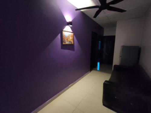 uma sala de estar com ventoinha de tecto e parede roxa em SENGGARANG HOMESTAY em Parit Kadir