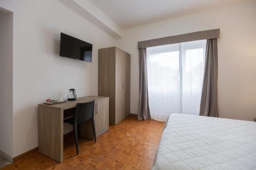a bedroom with a bed and a desk with a television at Hotel Nova Domus Aurelia in Rome