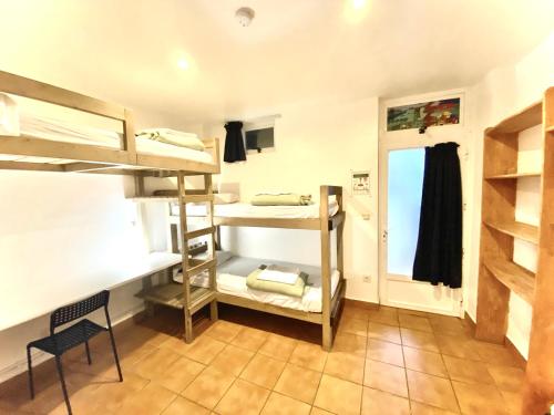a room with bunk beds and a chair and a window at Hostel albergue Paradiso in Hinojedo