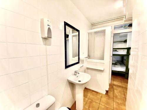 a white bathroom with a sink and a toilet at Hostel albergue Paradiso in Hinojedo