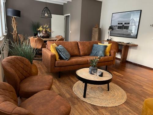 een woonkamer met een bruine bank en stoelen bij Vakantie appartement Sunndays in Valkenburg