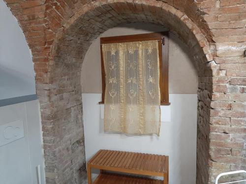 a brick archway with a window and a wooden bench at Assisi, Angolo di Matilde in Petrignano