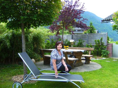 a woman is sitting in a chair in a garden at Ferienwohnung Millonigg in Vorderberg