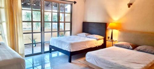 a bedroom with two beds and a large window at La Maison BLEUE in Cancún