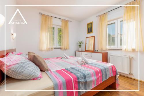 um quarto com uma cama com um cobertor listrado e janelas em Abacca House Fondole Croatia em Galižana